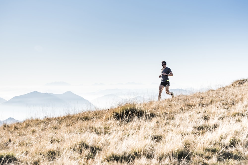 Un coureur de trail sur une crête, au-dessus d'une mer de nuages